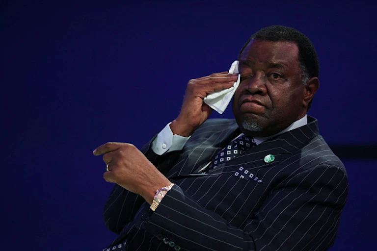 A man in a suit wiping his face with a handkerchief