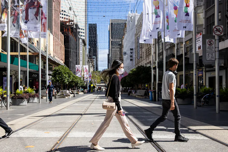 woman with masks walks across street