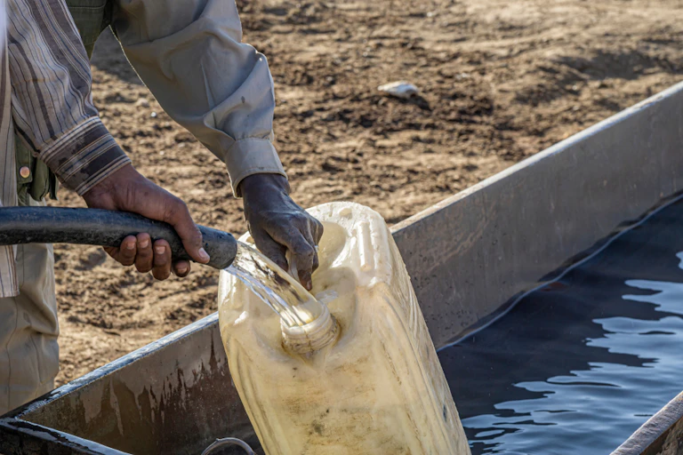 The hands of two men drawing water from a water well.