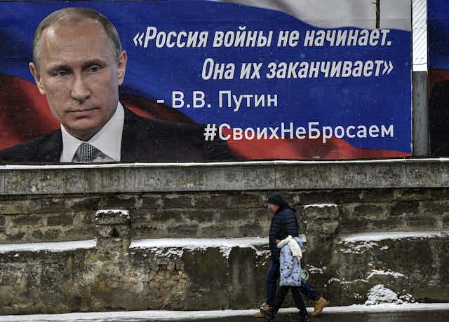 A man walks past a poster of the Russian president Vladimir Putin, on a wall in Crimea.