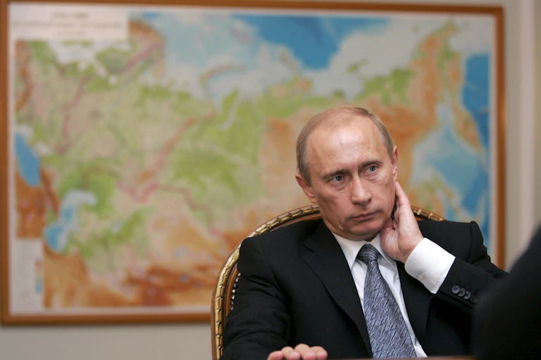 Vladimir Putin sitting in front of a map of Russia