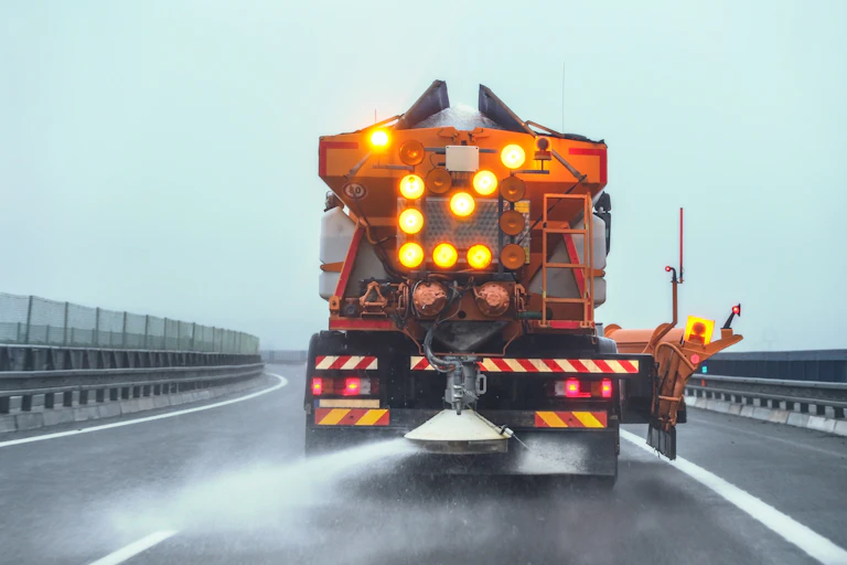 camion qui répand du sel sur la route en hiver