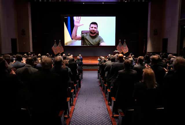 Ukrainian's President Volodymyr Zelenskyy waves his hand on a videolink with Congressmen and women gathered to hear him speak.