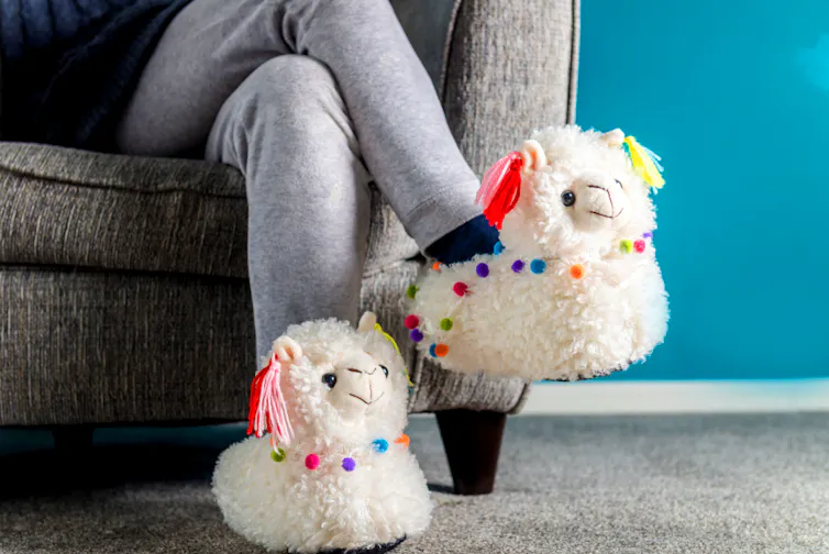 Une femme, jambes croisées, a mis des chaussons style peluche lama