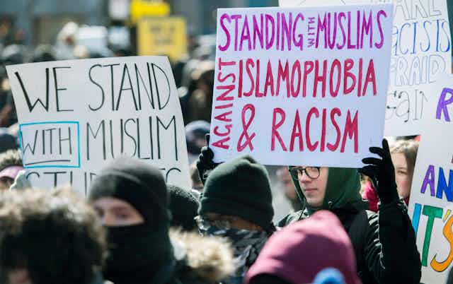 A man carries a sign that says Standing with Muslims Against Islamophobia and Racism.