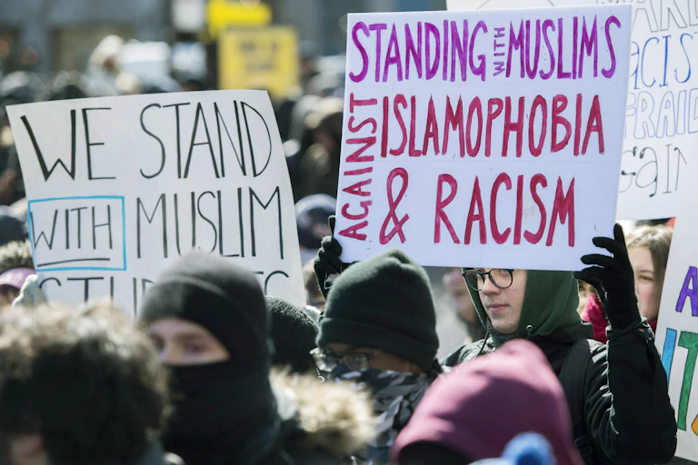 A man carries a sign that says Standing with Muslims Against Islamophobia and Racism.