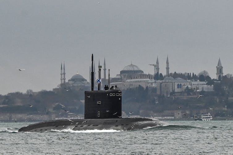 A black submarine is seen sailing before it submerges underneath the sea.