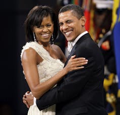 A Black man in a tuxedo dances with a black woman in a white gown.