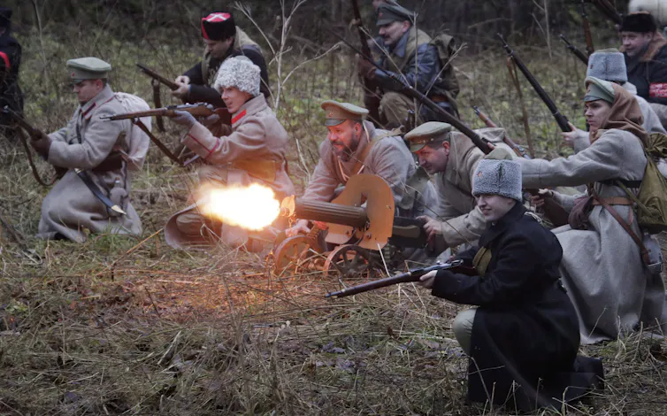People wearing military clothing kneeling and holding guns.