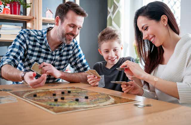 A father, son and mother play a board game