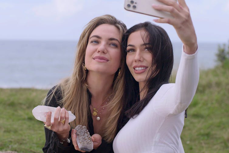 Two beautiful women hold crystals and take a selfie