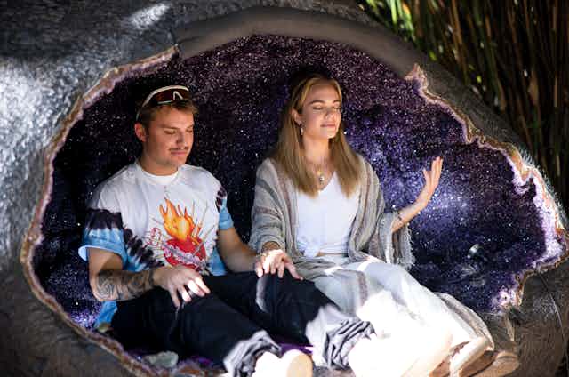A man and a woman sit in a giant geode
