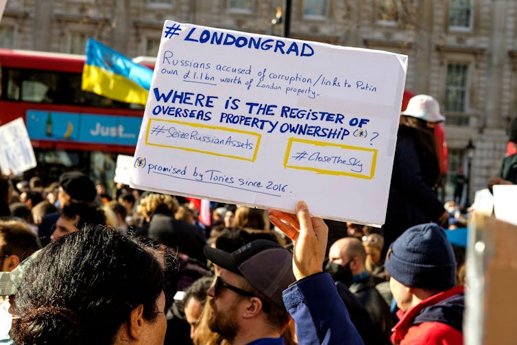 A protestor holds up a sign calling for actions against property fraud in London.