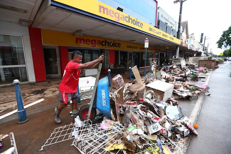 man empties wheelbarrow onto rubbish pile