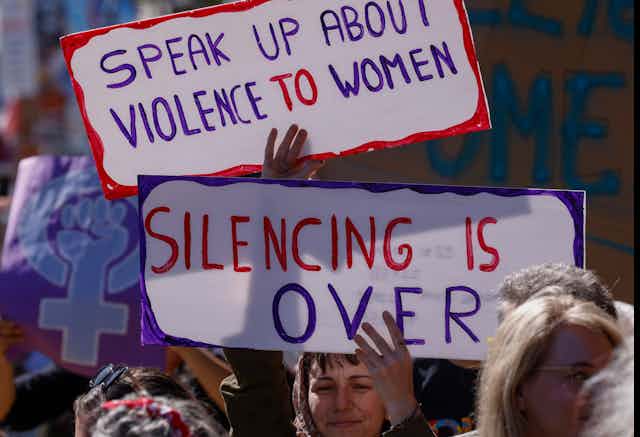 Protesters carry signs denouncing sexual violence against women