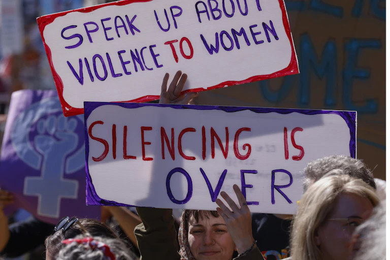 Protesters carry signs denouncing sexual violence against women