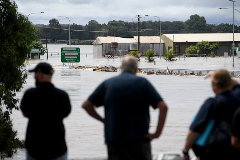 People watch the submerged Windsor Bridge