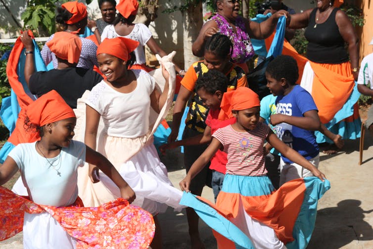 Young girls and older ladies twirl in colourful skirts.