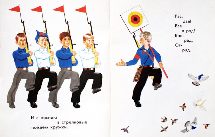Five boys marching and holding flags.