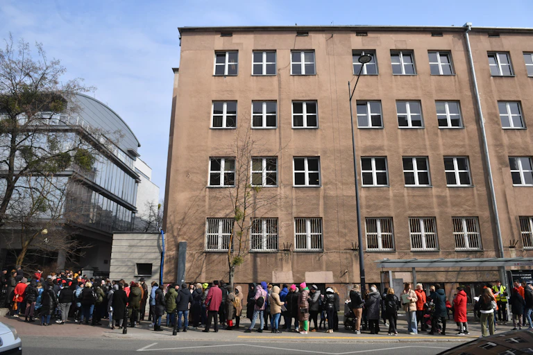 Refugees from Ukraine form a long ling outside a municipal building in Poland.