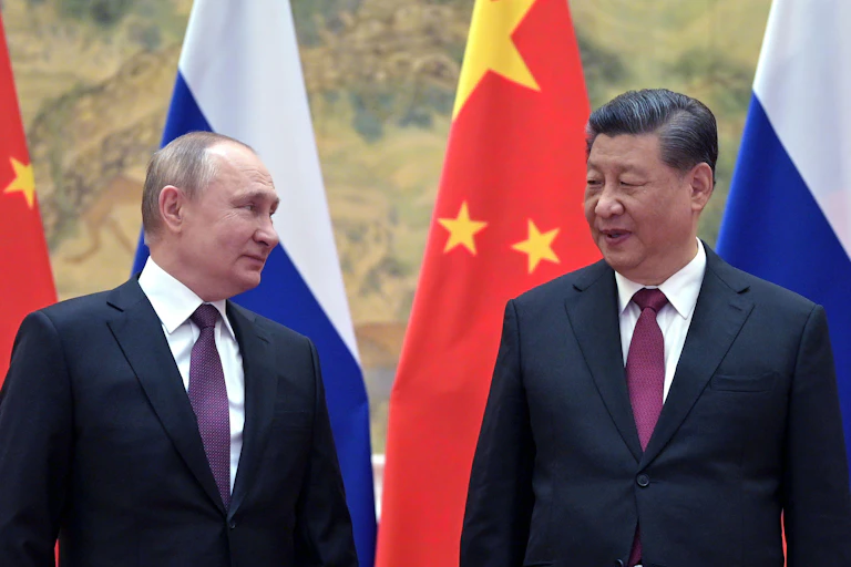 Two man standing in front of colourful flags.