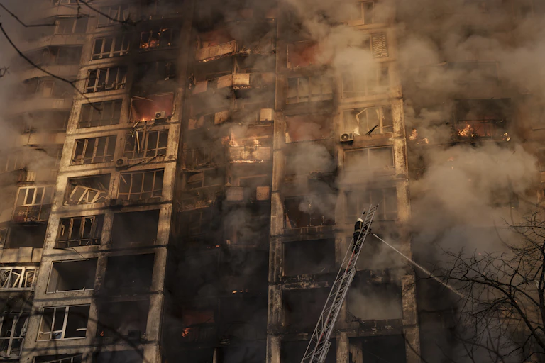 Firefighters point hoses at a burning apartment building.