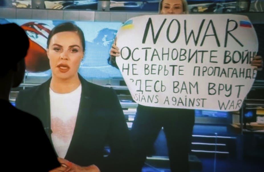 A woman interrupts a TV news bulletin in Russia with an anti-war protest.