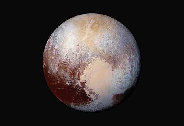 An images of the dwarf planet Pluto, showing colors of maroon, beige and white.