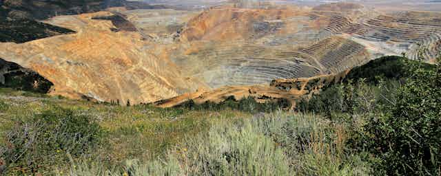 An overview of an open-pit mine with grasses in the foreground.