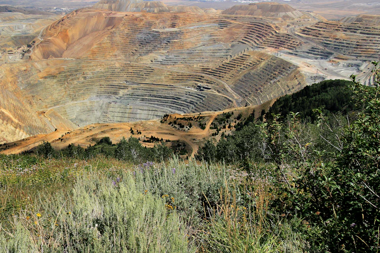 An overview of an open-pit mine with grasses in the foreground.
