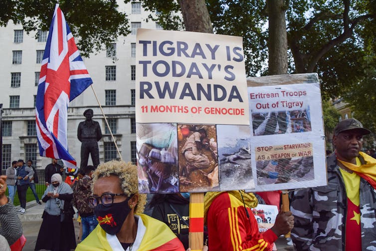 protestors in yellow and red hold signs.