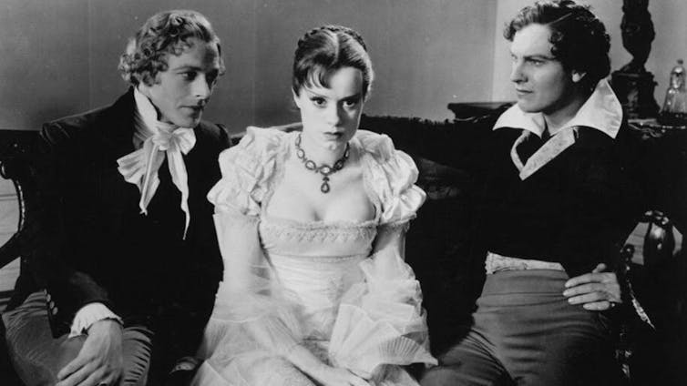 A pretty woman sitting between two men, looking anxious.