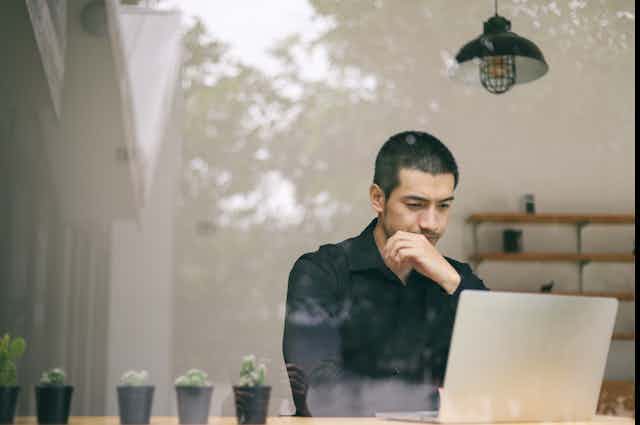 A man sits at a laptop.
