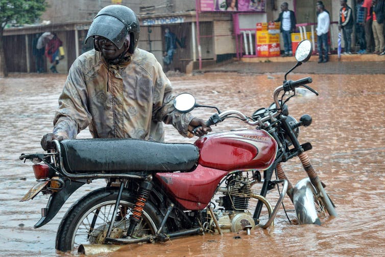 Man with motorcycle in flooded street