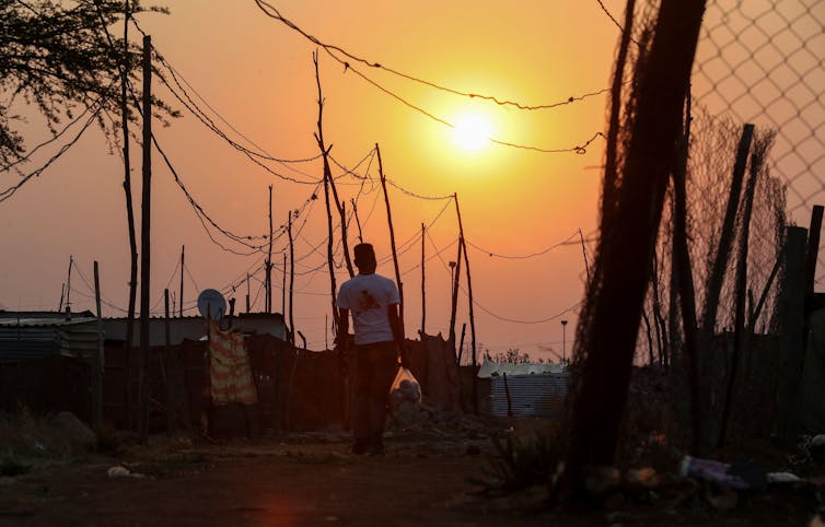 Man walks through informal settlement at sunset