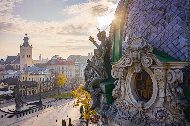 Sculpted roofs and a public plaza seen at sunset.