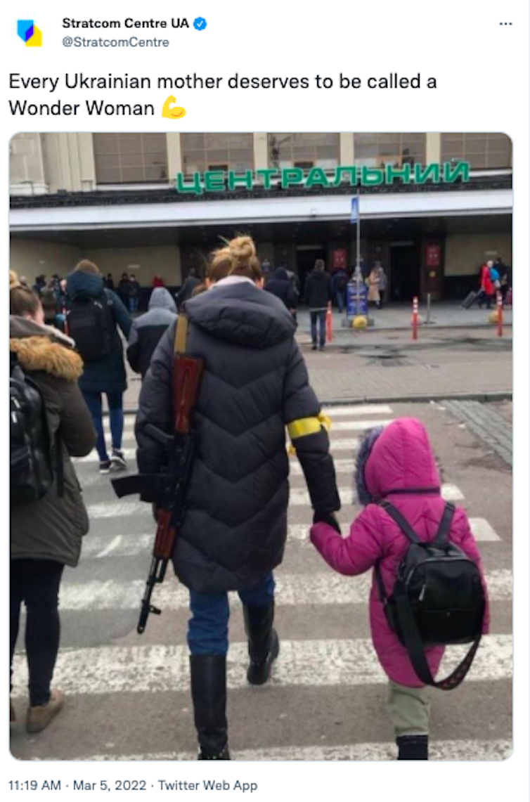 A woman in a winter coat holds a gun in her left hand and a child's hand in her right hand.