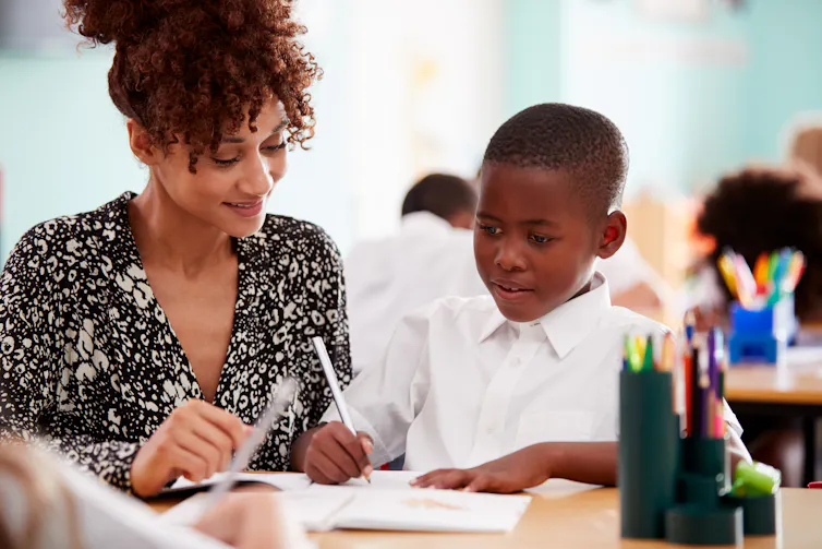 A lady helps a school child with his school work.