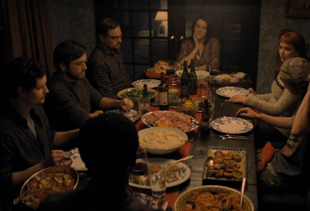 People seated around a dinner table with a spread of food and drinks.