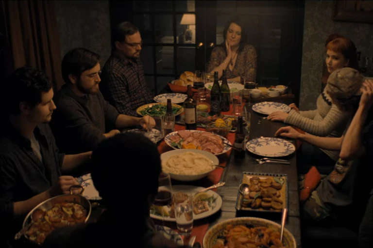 People seated around a dinner table with a spread of food and drinks.