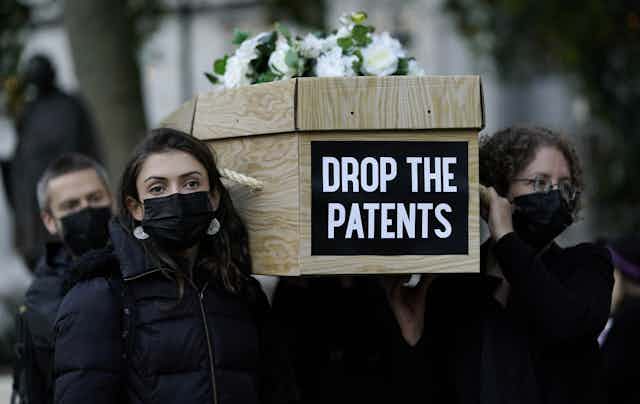 Women carrying a coffin as part of a public campaign to remove patents from COVID vaccines