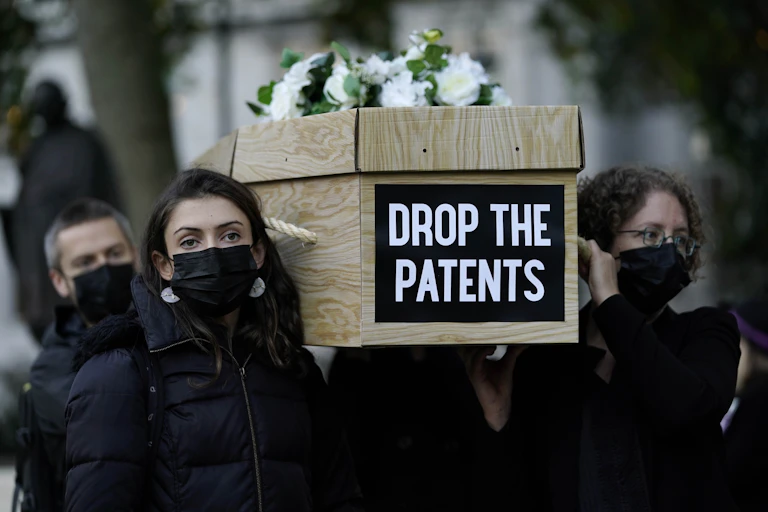 Women carrying a coffin as part of a public campaign to remove patents from COVID vaccines