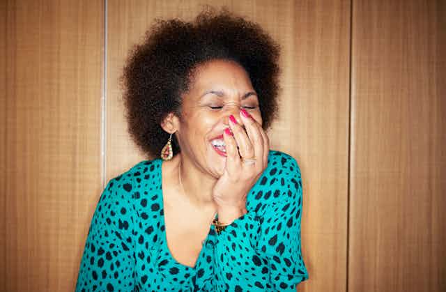 Woman covers her mouth with her hand while laughing.