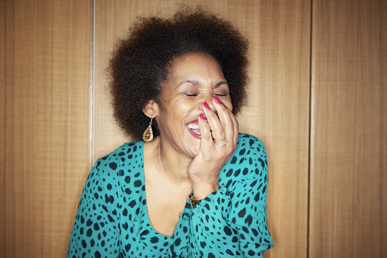 Woman covers her mouth with her hand while laughing.