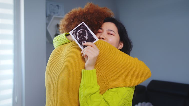 Couple embracing with ultrasound image of baby