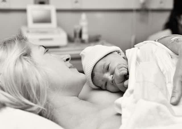 Black and white hospital scene,mother cuddling newborn