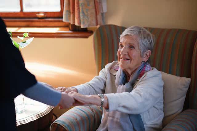 Aged care resident takes a nurse's hand