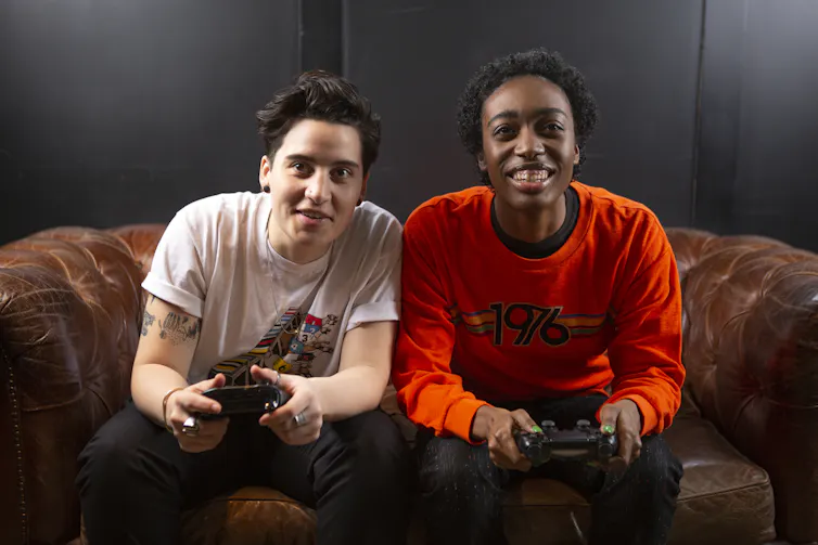 Two people on a sofa playing video games laughing