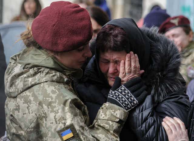 A female Ukrainian soldier comforts a crying woman