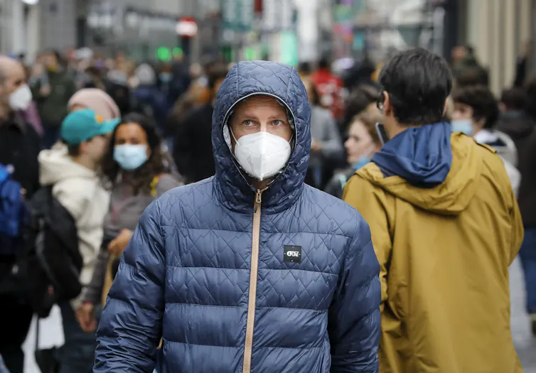 A man in Belgium wearing a mask walking down a street